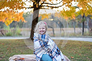 Cute little girl wrapped in a blanket on a blustery fall day