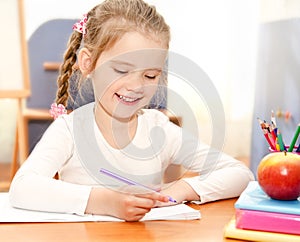 Cute little girl is writing at the desk in preschool