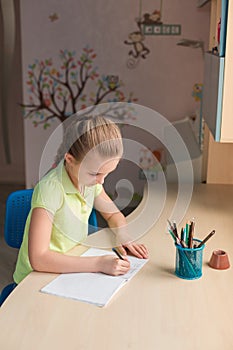 Cute little girl writing her homework at the table