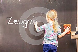 Cute little girl writing Zeugnis on chalkboard - Translation Testimony