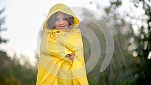 Cute little girl in a yellow raincoat in the rain