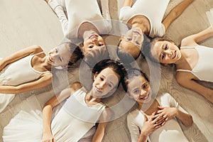 Cute little girls ballerinas lying on floor in circle