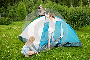 Cute little girls helping their parent to set up a tent on a campsite. Active lifestyle, family recreational weekend