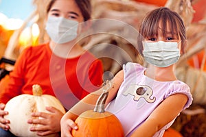 Cute Little Girls Holding Their Pumpkins At A Pumpkin Patch Wearing Medical Face Masks