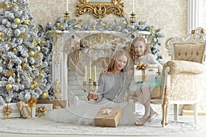 Cute little girls with presents near decorated Christmas tree
