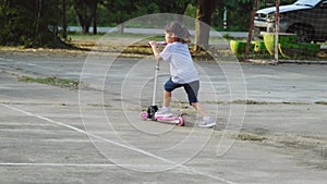 Cute little girls riding scooter on road in park outdoors on summer day. girl playing outdoors with scooter. Active leisure and ou