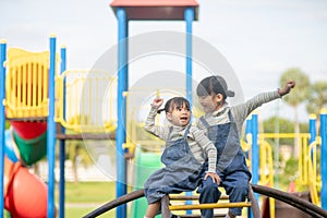Cute little girls siblings having fun on playground outdoors on a sunny summer day. active sport leisure for kids