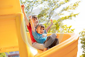 Cute little girls siblings having fun on playground outdoors on sunny summer day. Children on plastic slide. Fun activity for kid