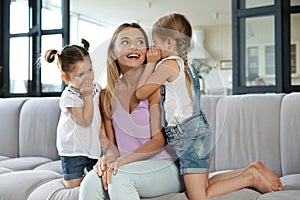 Cute little girls telling secrets to their mother