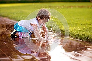 Cute little girl sitting in puddle