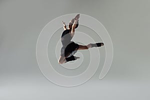 Cute little gymnast doing stag leap on white background