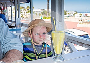 Cute little happy boy anticipating drinking a banana milkshake