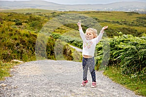 Cute little happy toddler girl running on nature path in Connemara national park in Ireland. Smiling and laughing baby