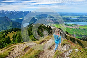 Cute little hiker enjoying picturesque views from the Tegelberg mountain, a part of Ammergau Alps, located nead Fussen town, Germa