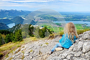 Cute little hiker enjoying picturesque views from the Tegelberg mountain, a part of Ammergau Alps, located nead Fussen town, Germa