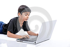 Cute little Indian/Asian boy studying or playing game with laptop computer
