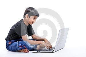 Cute little Indian/Asian boy studying or playing game with laptop computer