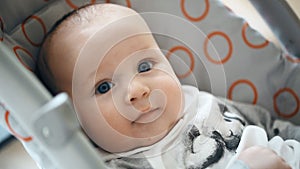 Cute little infant boy sitting in stroller, looking and smiling. Innocence and child emotions