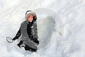 Cute Little Kid All Bundled Up for Winter is Building a Tunnel in a Snow Pile