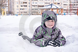 Cute little kid boy in colorful winter clothes laying down on . Active outdoors leisure with children in . Happy child.