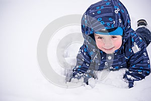 Cute little kid boy in colorful winter clothes making snow angel