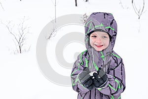 Cute little kid boy in colorful winter clothes making snow angel