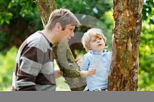 Cute little kid boy enjoying climbing on tree with father, outdo