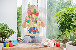 Cute little kid boy with playing with lots of colorful plastic blocks indoor. Active child having fun with building and