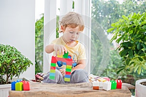 Cute little kid boy with playing with lots of colorful plastic blocks indoor. Active child having fun with building and