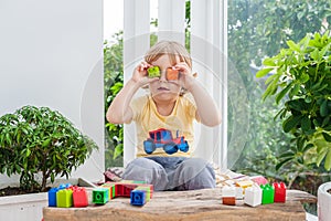 Cute little kid boy with playing with lots of colorful plastic blocks indoor. Active child having fun with building and