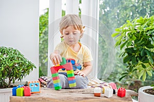 Cute little kid boy with playing with lots of colorful plastic blocks indoor. Active child having fun with building and