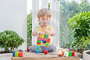 Cute little kid boy with playing with lots of colorful plastic blocks indoor. Active child having fun with building and creating o