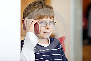 Cute little kid boy wearing eye glasses speaking on cellular phone