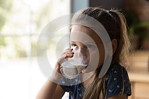 Cute little kid girl drinking glass of fresh yoghurt.