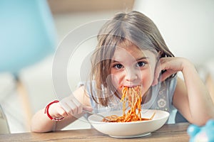 Cute little kid girl eating spaghetti bolognese at home