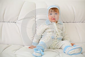 Cute little kid in knitted suit and hat sits on photo