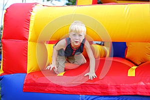 Cute Little Kid Playing on Inflatable Bounce House Obstacle Course at American Festival