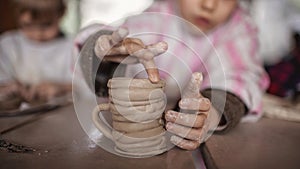 Cute little kids playing together with modeling clay in pottery workshop, craft and clay art