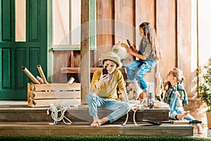 Cute little kids sitting on porch with different traveling items