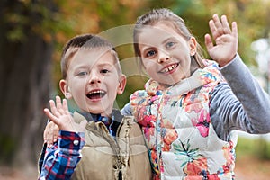 Cute little kids waving hello in the park