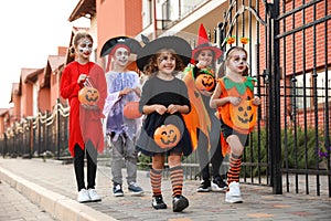 Cute little kids wearing Halloween costumes going trick-or-treating outdoors