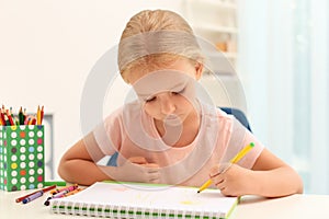 Cute little left-handed girl drawing at table