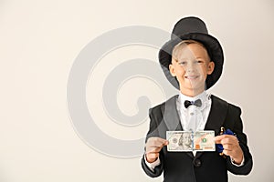 Cute little magician showing trick with money on white background