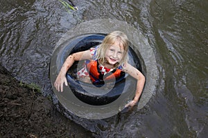 Cute Little Muddy Girl Child Swimming in Tube in River