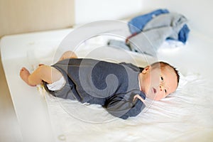 Cute little newborn baby boy lying on a changing table. Portrait of tiny new baby at home