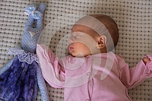 cute little newborn baby girl peacefully sleeps with toy bunny