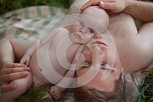 Cute little newborn boy and father relaxing in the park or forest. Fatherly love