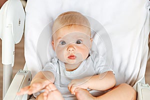 Cute little newborn girl with smiling face looking at camera on white background. Infant baby resting playing lying down