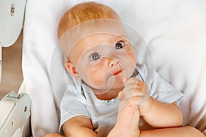 Cute little newborn girl with smiling face looking at camera on white background. Infant baby resting playing lying down