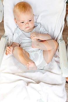 Cute little newborn girl with smiling face looking at camera on white background. Infant baby resting playing lying down